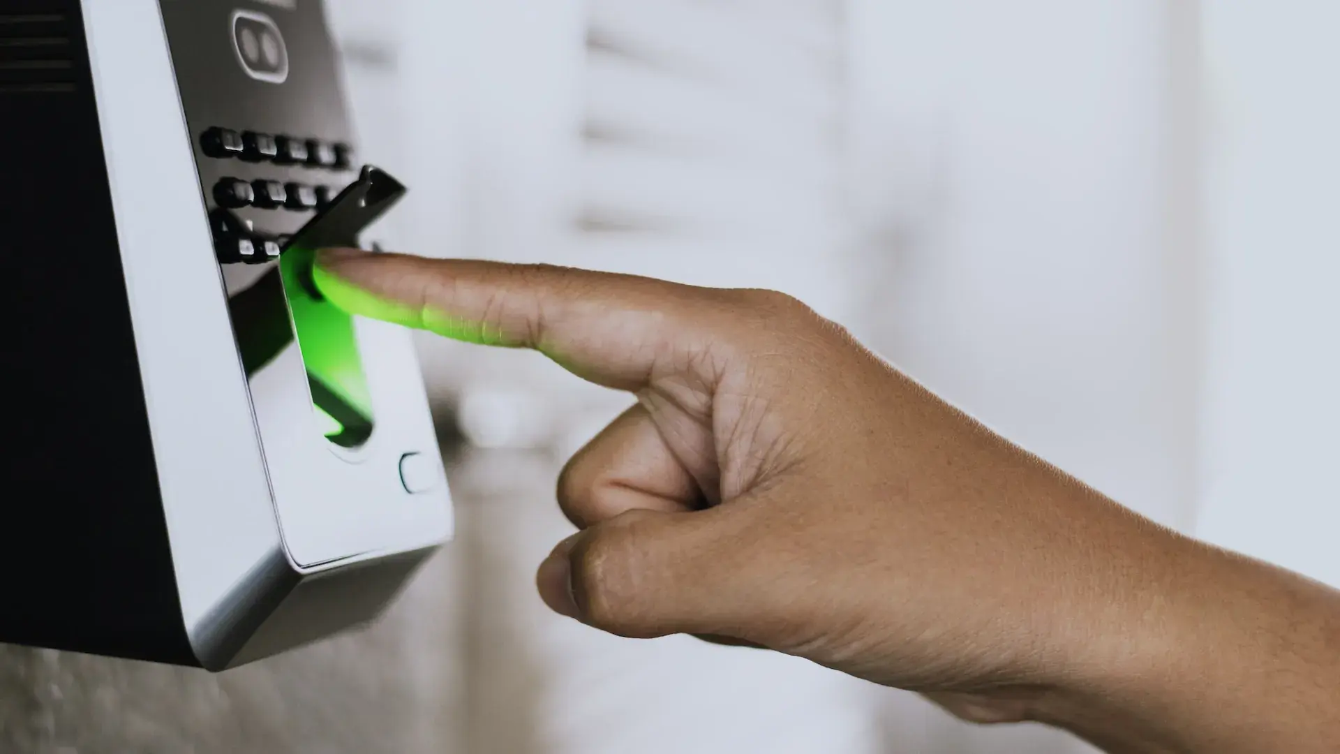 Finger on a fingerprint access control scanner at a business entrance