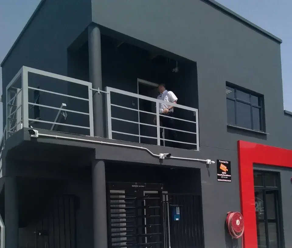 Access control installation: full-height turnstile and bullet CCTV cameras at a building entrance protected by CCTV Security Surveillance