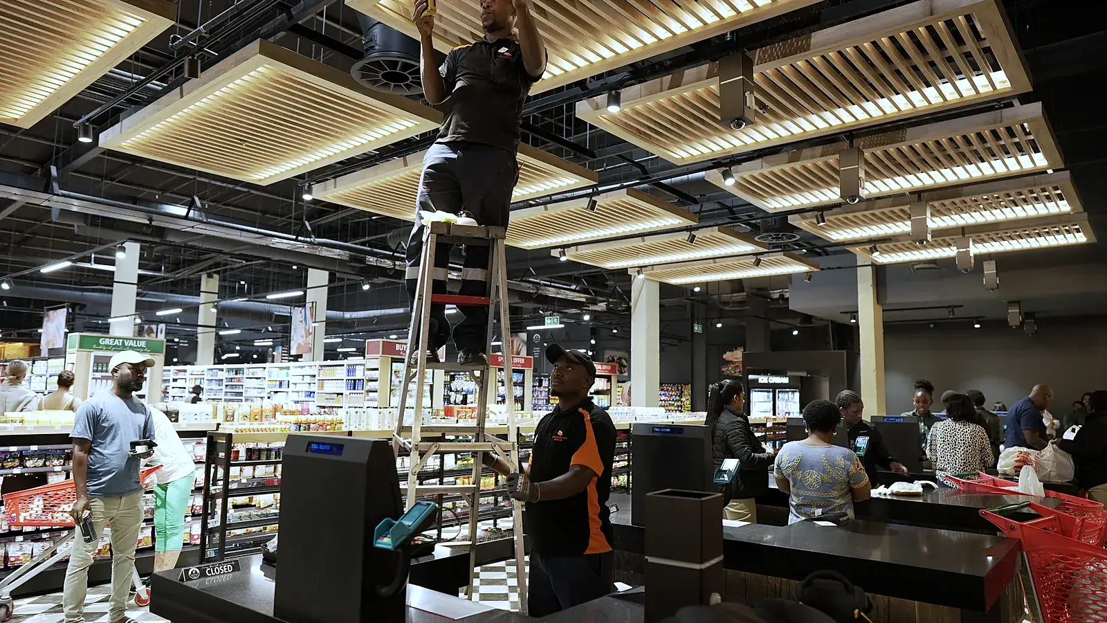 CCTV Security Surveillance installation team mounting a camera above a busy store floor