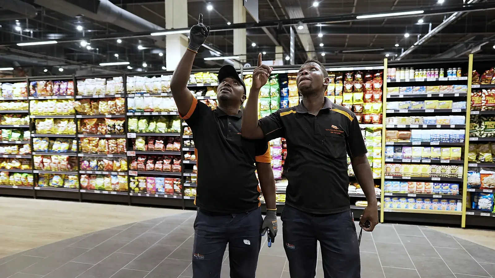CCTV Security Surveillance technicians checking camera coverage in a retail store aisle